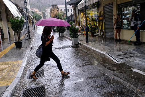 Pedestrians protect themself from the rain with umbrellas during a rainfall in Athens, Greece on August 23, 2022.