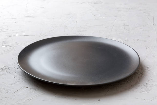 Perspective view of empty black plate on cement background. Empty space for your design