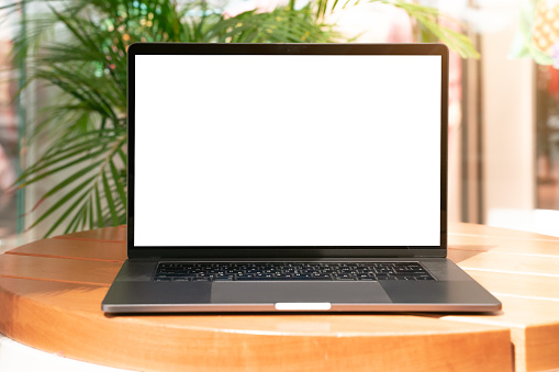 Laptop with white screen in vacation situation. Empty copy space, blank screen mockup. Soft focus laptop with interor background. Vacation, treveling and remote work concept.