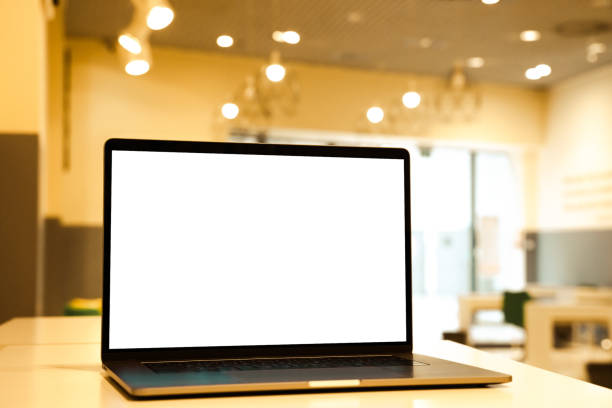 istock Laptop with white screen in business office or shopping mall. Empty copy space, blank screen mockup. Soft focus laptop with interor background. Travel, study and office work concept. 1417443451