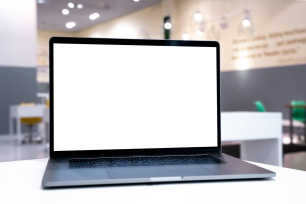 istock Laptop with white screen in business office or shopping mall. Empty copy space, blank screen mockup. Soft focus laptop with interor background. Travel, study and office work concept. 1417443452