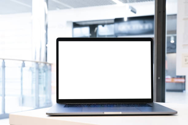 istock Laptop with white screen in business office or shopping mall. Empty copy space, blank screen mockup. Soft focus laptop with interor background. Travel, study and office work concept. 1417443453