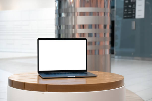 istock Laptop with white screen in business office or shopping mall. Empty copy space, blank screen mockup. Soft focus laptop with interor background. Travel, study and office work concept. 1417443474