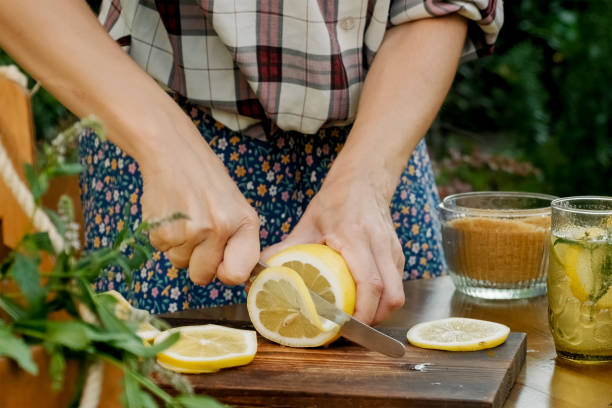 istock Female hands making summer lemonade beverage outdoors. 1417443700