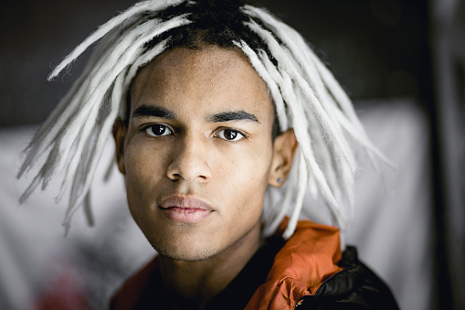 Male portrait of young guy with white dreadlocks. Multiracial person with dark skin indoors, lifestyle photography with handsome people.