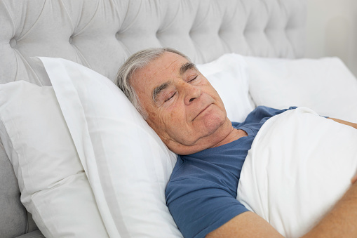Senior man is sleeping in his bed.