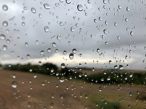 Rain water falls on a transparent umbrella with a natural background