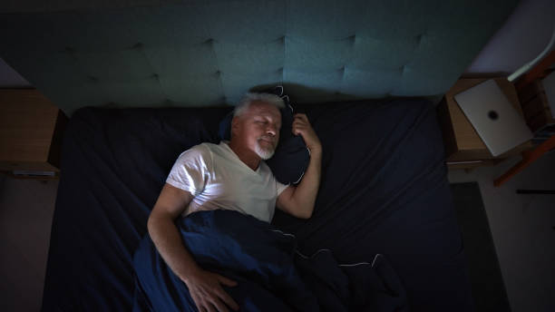 Anxious, mature man trying to sleep at night. Dealing with sleeping disorder stock photo