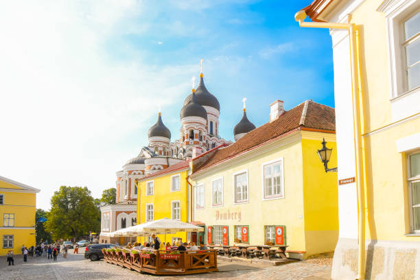 Tourists sightsee and enjoy lunch at a sidewalk cafe on Toompea Hill alongside the Alexander Nevsky Russian Orthodox Cathedral on a summer day in Tallinn, Estonia Tourists sightsee and enjoy lunch at a sidewalk cafe on Toompea Hill alongside the Alexander Nevsky Russian Orthodox Cathedral on a summer day in Tallinn, Estonia town wall tallinn stock pictures, royalty-free photos & images