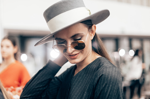 Female portrait of beautiful woman who working fashion model at the fashion week show. Backstage photography, behind the scenes of new clothing collection. Girl wear eyeglasses and hat.