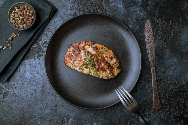 istock Grilled chicken Breasts on black plate on dark stone table top view 1417463390