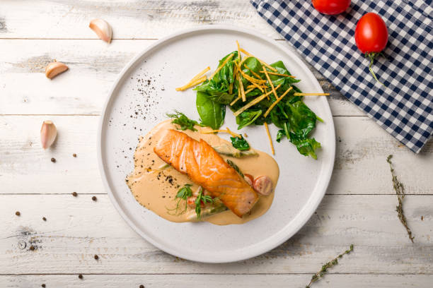 istock Salmon steak on the grill with spinach on white plate on white wooden table top view 1417467410