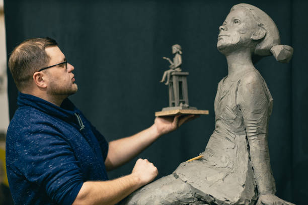 istock Man sculptor creates sculpt bust clay human woman sculpture. Statue craft creation workshop 1417469564