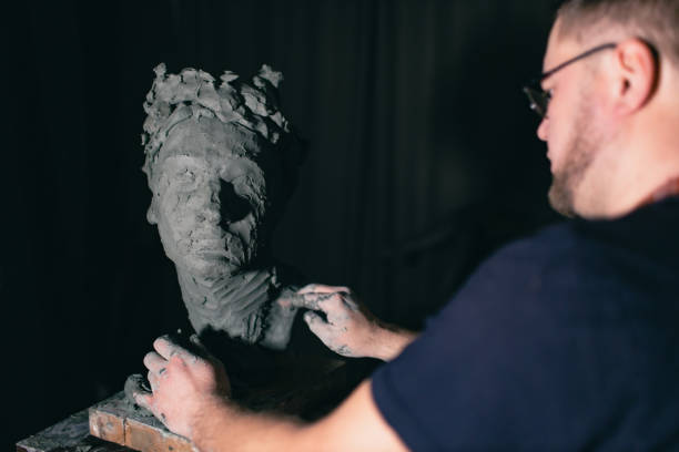 istock Man sculptor creates sculpt bust clay human woman sculpture. Statue craft creation workshop 1417469571