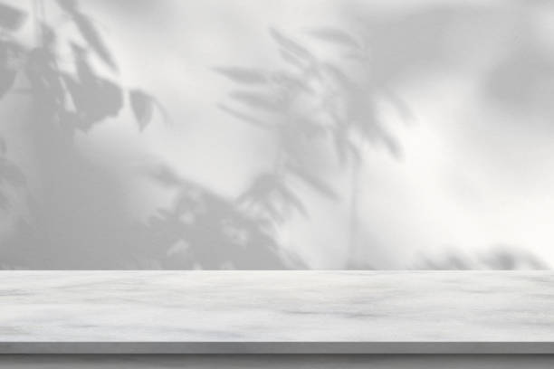 istock Marble table with tree shadow drop on white wall background for mockup product display 1417469682