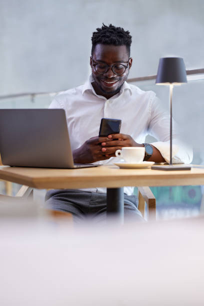 istock A busy African casual businessman sits in a cafeteria, having a phone call with a client while typing on the laptop. 1417476870