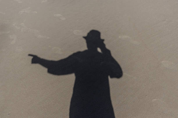 Shadow of a man on the beach sand pointing to the side. Praia do Guaibim, coast of the sea of Bahia, Brazil