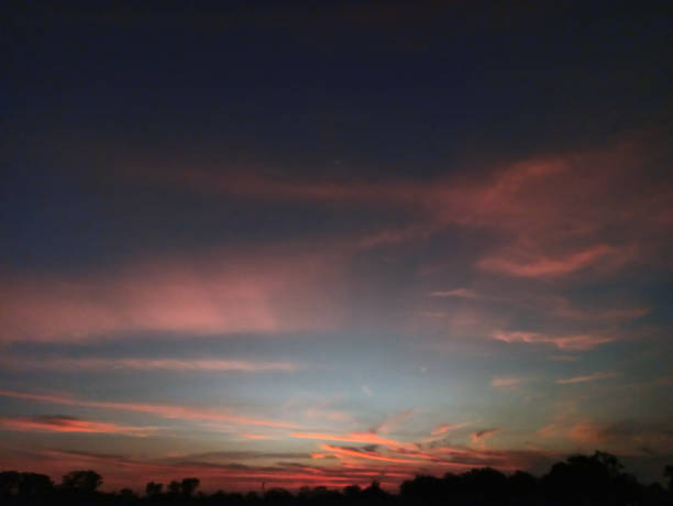 Low angle view of scattered clouds against a blue cloud background with yellow gradations due to the setting sun