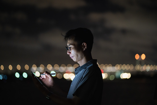 man using tablet by the sea at night