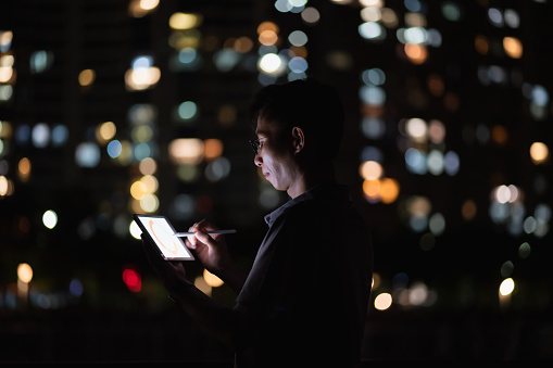 Man using tablet computer outdoors on the background of thousands of lights