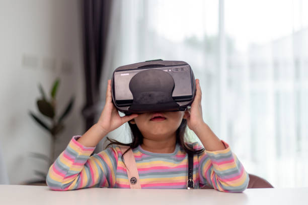 istock Child with virtual reality headset sitting behind table indoors at home 1417486478