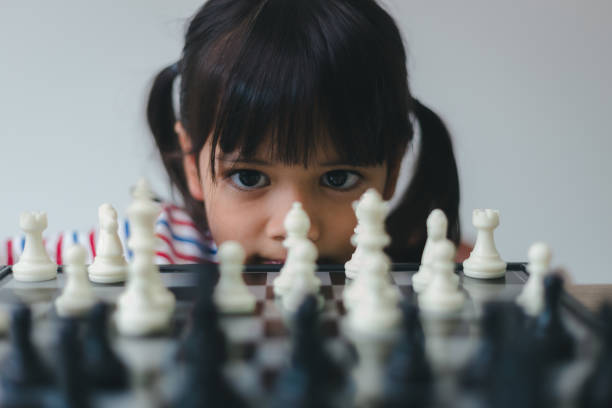 petite fille asiatique jouant aux échecs à la maison.une partie d’échecs - chess skill concentration intelligence photos et images de collection