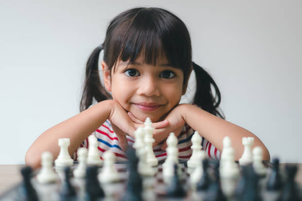 asiatisches kleines mädchen, das zu hause schach spielt.eine partie schach - concentration chess playing playful stock-fotos und bilder