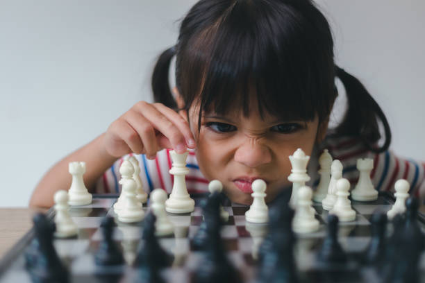 niña asiática jugando al ajedrez en casa.una partida de ajedrez - chess skill concentration intelligence fotografías e imágenes de stock