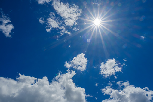 cloudscape image of shinning sun over blue sky and clouds