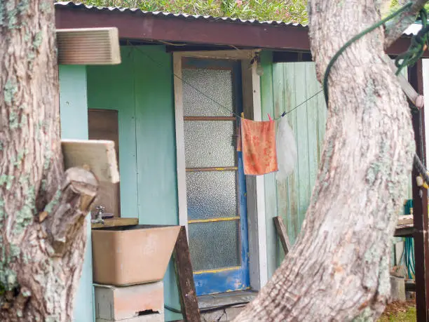 Rustic exterior to small accommodation building with orange towel hanging with closed door.