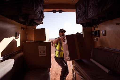 Delivery post man retrieving a package from his van at Monument Valley - Utah