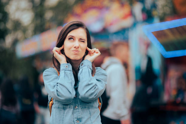 unglückliche frau, die von lauter musik auf dem lauten outdoor-jahrmarkt gestört wird - human finger audio stock-fotos und bilder