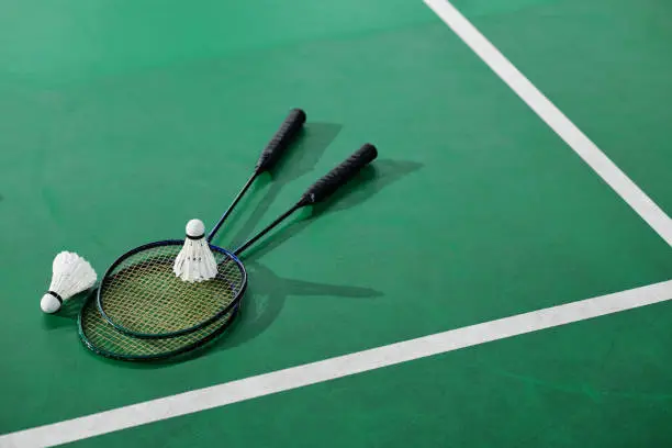 Shuttlecoks and badminton rackets on green court floor