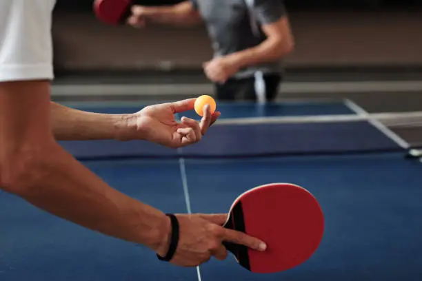 Hands of young man serving ping pong ball with topspin