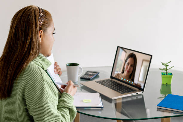 istock Woman studying and pointing to a notebook with her finger while in an online class with her laptop from home. 1417524135