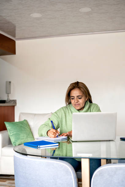 istock Woman studying and writing in her diary while sitting at the table at home. 1417524149
