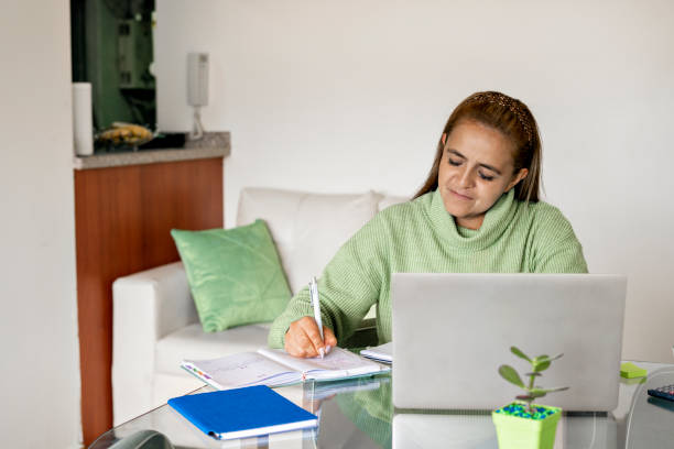 istock Woman studying and writing in her diary while sitting at the table at home. 1417524164
