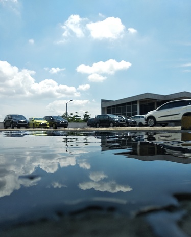 car park with puddles on a beautiful blue cloud background