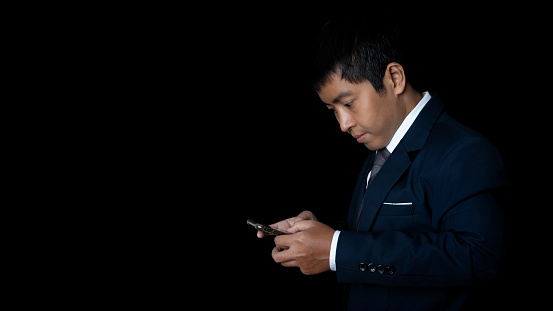 Portrait of businessman using smartphone. Human emotion face expression concept. Studio shot on black background. copy space.