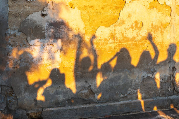istock Shadows of dancing people on an old stone wall at sunset time. 1417530552