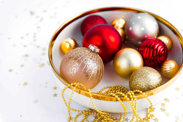 holidays concept - shiny christmas balls on white background with garland and confetti