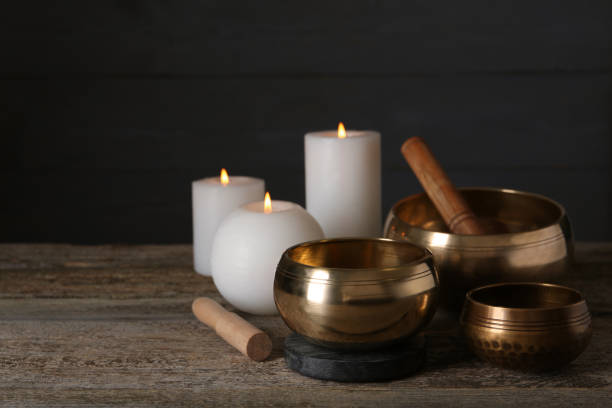 istock Golden singing bowls, mallets and burning candles on wooden table, space for text 1417543346