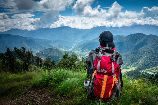 September 16th 2021 Uttarakhand INDIA. A solo hiker Hikers with a backpack looking towards the valley of Mountains. Nag Tibba trek of Lower Himalayas.