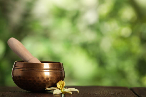 istock Golden singing bowl, mallet and flower on wooden table outdoors, space for text 1417544855