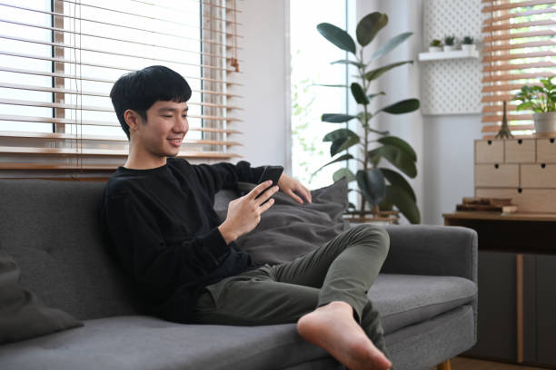 istock Handsome man resting on couch and typing text message on mobile phone, enjoying chatting online with his friends. 1417547879