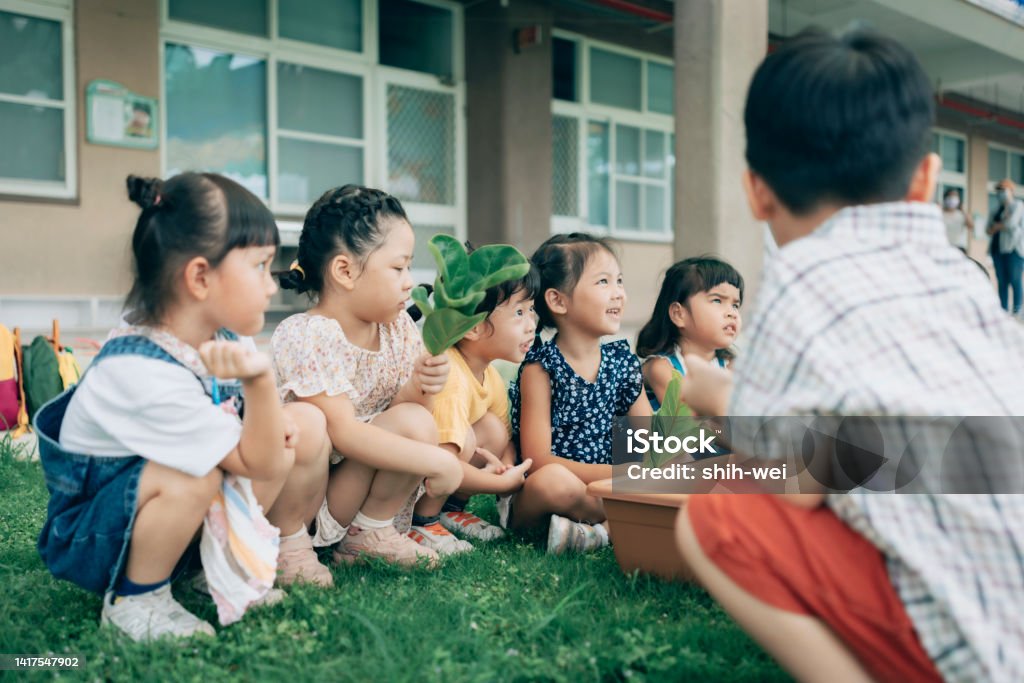 Pre- school teacher teaching children about plants  in nursery, Educational Environment and Life Course from Childhood Childhood Stock Photo