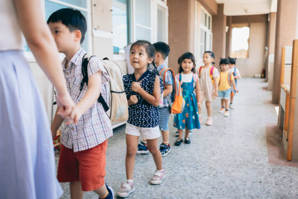 professor de pré-escola orienta e organiza alunos esperando na fila entrando em sala de aula - preschooler child chinese ethnicity asian ethnicity - fotografias e filmes do acervo