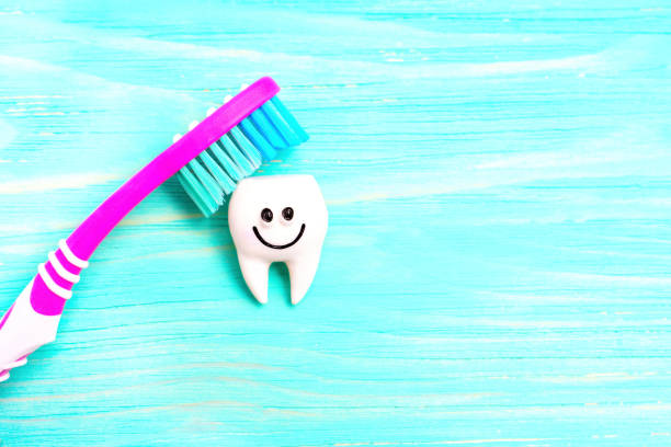 Colorful toothbrush touching a funny tooth character isolated on a blue wooden background with copy space.