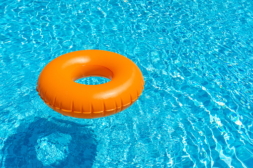 Anillo naranja flotando en piscina azul. Anillo inflable, concepto de descanso photo