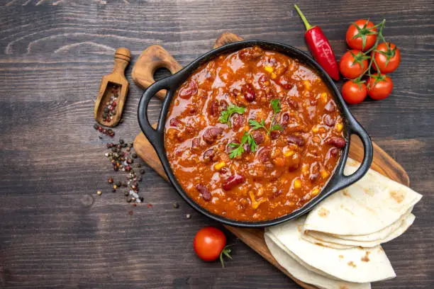 Photo of Bean and corn soup or ragout, red bean stew on a wooden background. Food Protein Vegan dish